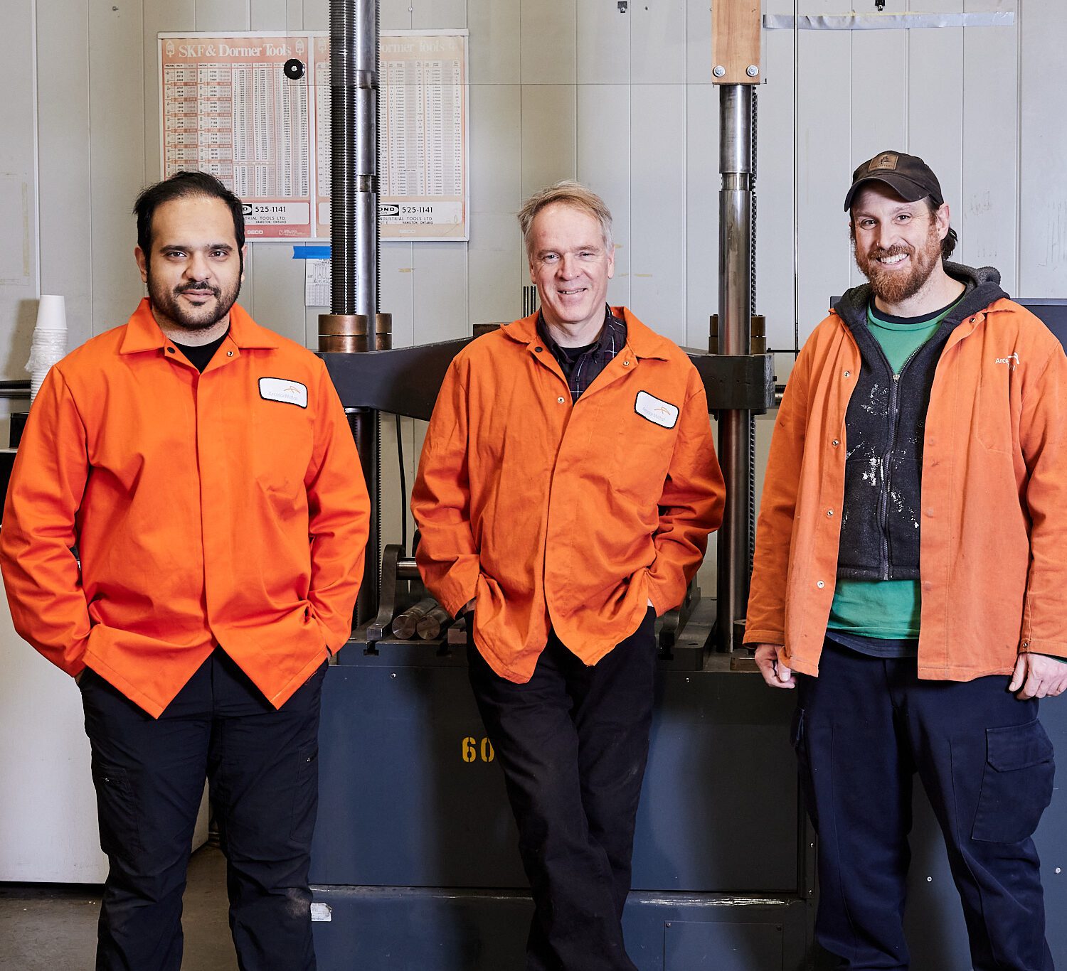 Test lab staff smiling in front of equipment, wearing orange coats