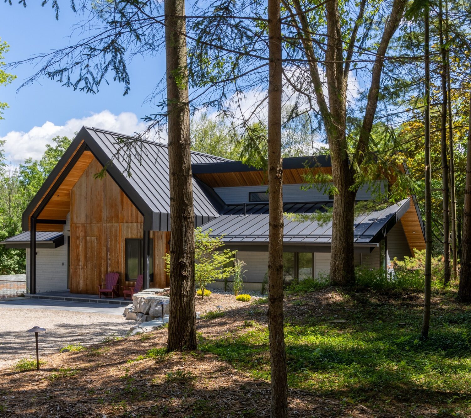 Cabin with rusted Indaten weathered steel exterior, viewed through forest trees