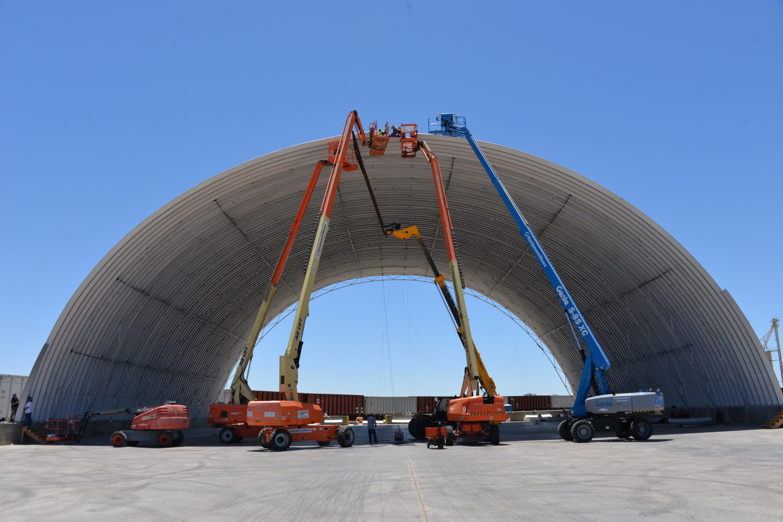 SkyJacks and workers on top of Large Quonset Hut Structure being built