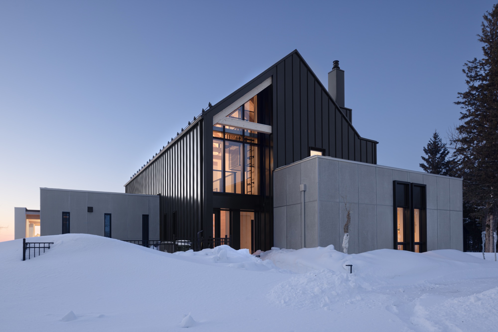Exterior view of residence showing the black exterior paneling and concrete add-ons.
